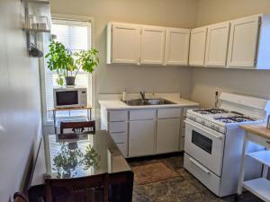 uma cozinha com armários brancos, um fogão e um lavatório em Moline 1 BR Near TaxSlayer and Downtown em Moline