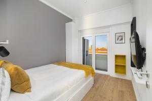 a white bedroom with a bed and a tv at WHome | 270º Panoramic View Premium Apartment in Lisbon