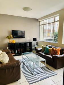 a living room with two couches and a glass table at Live, explore & entertain in the City! in Cape Town