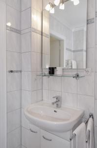 La salle de bains blanche est pourvue d'un lavabo et d'un miroir. dans l'établissement F32 13 Buhne 32, à Westerland