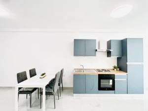 a kitchen with blue cabinets and a table with chairs at SUNSHINE SUITS - BRAND NEW APARTMENTS in Msida