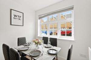 a dining room with a table with chairs and a window at Modern 4 Bedroom House with Parking Basildon in Laindon