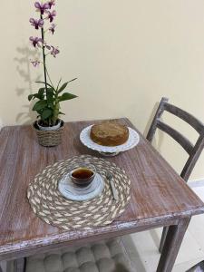 una mesa con un pastel y una taza de café. en Charmoso Village Praiano en Lauro de Freitas