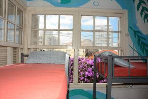 a bedroom with a bed and a window with purple flowers at AKKUI HOSTEL in São Paulo