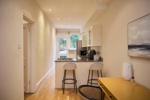 een keuken met 2 barkrukken en een aanrecht bij The West Kensington Hideout - Cozy 2BDR Flat with Garden in Londen