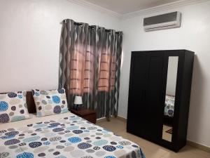 - une chambre avec un lit, une commode et un miroir dans l'établissement RESIDENCE IVOIRE, à Accra