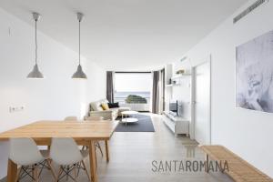 una sala de estar blanca con mesa de madera y sillas en Santa Romana Apartments & Suites en Caldes d'Estrac