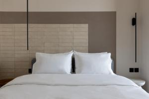 - un lit blanc avec des draps et des oreillers blancs dans l'établissement CLOCK Central Stay, à Xánthi
