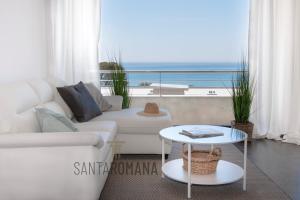 Sala de estar con sofá blanco y vistas al océano en Santa Romana Apartments & Suites en Caldes d'Estrac