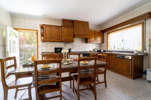 a kitchen with wooden cabinets and a table and chairs at Gondomar Guimarães - Moradia V3 com piscina natural by House and People in Guimarães