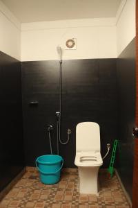 a bathroom with a toilet and a blue bucket at Jungle Woods 900kandi in Wayanad