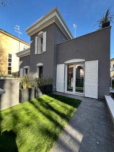 a gray house with a lawn in front of it at VILLA MONTI SUITES&APARTS in Cesenatico
