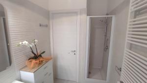 a white bathroom with a shower and a vase of flowers at Civico 47 in Ogliastro Cilento +10 photos