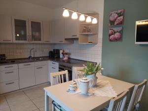 a kitchen with white cabinets and a table with chairs at Ferienwohnung am Hünenweg in Berge