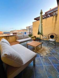 eine Terrasse mit Sofas, einem Tisch und einem Sonnenschirm in der Unterkunft Casa Melina in Marina di Ragusa