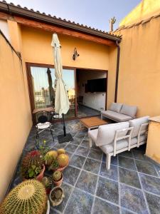 eine Terrasse mit einem Sofa und einem Regenschirm und einigen Pflanzen in der Unterkunft Casa Melina in Marina di Ragusa