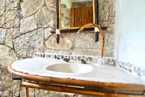uma casa de banho em pedra com um lavatório e um espelho em Cabañas Tosepan Kali em Cuetzalan