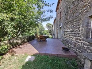 un patio con tavolo e sedie accanto a un edificio in mattoni di La maisonnée Auvergnate ad Auzelles