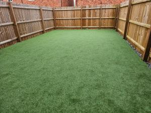 a backyard with a fence and green grass at Remarkable and modern house in Rugby England in Rugby