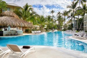 una piscina in un resort con sedie a sdraio e palme di Impressive Premium Punta Cana - All Inclusive a Punta Cana