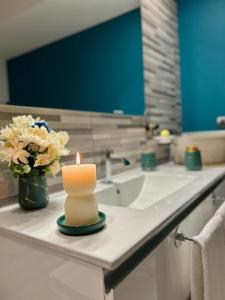 Una vela sentada en el mostrador del baño junto a un lavabo. en Suite Deluxe - Jacuzzi - Private Parking en Turín