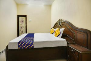1 dormitorio con 1 cama con cabecero de madera en SPOT ON Raja Guest House, en Jalandhar