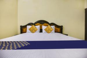 Una cama con almohadas amarillas y blancas. en SPOT ON Raja Guest House, en Jalandhar