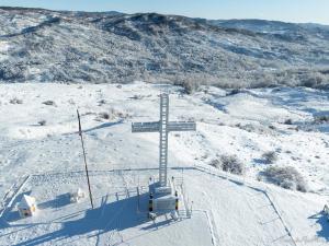 a cross on the top of a snow covered hill at CARPATINA Ruustic House in Runcu