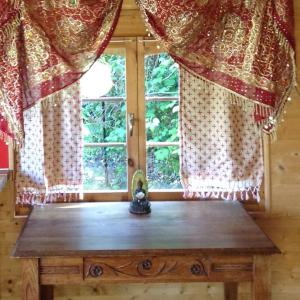une table en bois devant une fenêtre avec des rideaux dans l'établissement Le Paradis caché : Chalet Shangri-La, à Villennes-sur-Seine