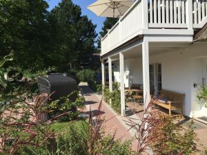 a patio with a white house and an umbrella at Schäferkate Sierksdorf in Sierksdorf