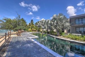 una piscina junto a un edificio y al océano en Le Turquoise - Beachfront, en Cap Malheureux