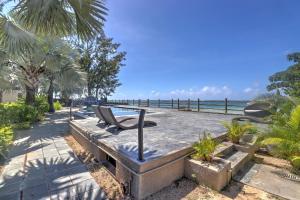 a chair sitting on a bench next to the ocean at SG5 l Le Turquoise - third line building - Beachfront Residence in Cap Malheureux