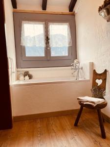 a bathroom with a window and a chair and a tub at Bnbook Ca Du Val in Terrabona