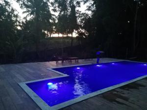 a blue swimming pool with lights in a yard at Casa Amadou com grande piscina em Boipeba in Ilha de Boipeba