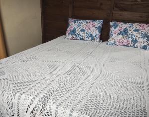 ein weißes Bett mit zwei Kissen darüber in der Unterkunft Casa das Embaúbas 5 in São José