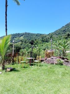 a park with a table and chairs in the grass at O Canto da Rosa Quarto Quádruplo in Paraty