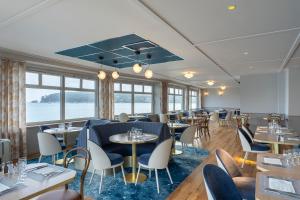 un restaurant avec des tables, des chaises et des fenêtres dans l'établissement Hôtel Morgat Le Grand Hôtel De La Mer, à Crozon