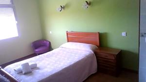 a bedroom with a bed and a purple chair at hostal restaurante galicia in Villardefrades