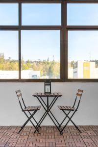 a table and two chairs in a room with windows at East River - T4 junto ao Altice Forum - Braga in Braga