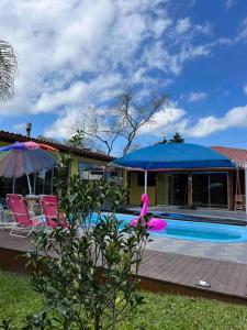 ein Haus mit einem Pool mit einem blauen Sonnenschirm in der Unterkunft Bem vindos a Vila da Paz Itaara in Itaara