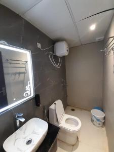 een badkamer met een wit toilet en een wastafel bij Green Valley Luxurious Hotel in Ghaziabad