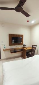een kamer met een bureau, een tv en een plafondventilator bij Green Valley Luxurious Hotel in Ghaziabad