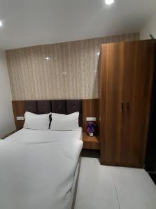 een slaapkamer met een groot bed en een houten kast bij Green Valley Luxurious Hotel in Ghaziabad