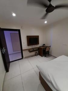 een slaapkamer met een bed, een tv en een bureau bij Green Valley Luxurious Hotel in Ghaziabad