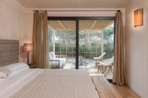 a bedroom with a bed and a sliding glass door at Glamping Terre di Sacra in Tuscany in Capalbio
