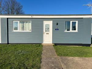 una casa gris con una puerta y dos ventanas en Saltwater Chalet, en Kessingland