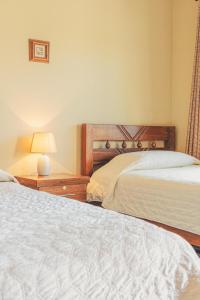 1 dormitorio con 2 camas y una lámpara en una mesa en Hostal Claure, en Toro Toro