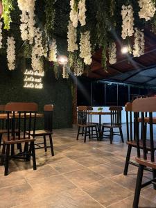una zona de comedor con mesas, sillas y flores blancas en Hostal Claure, en Toro Toro