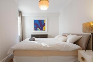 ロンドンにあるStylish Kensington Courtyard Apartmentの白いベッドルーム(大型ベッド1台、ランプ付)