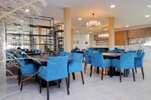 um restaurante com cadeiras azuis e uma sala de jantar em Siena Hills Apartments em Siena